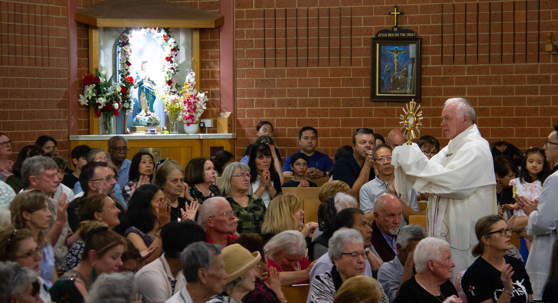 Fr Rozo carrying the Blessed Sacrament through the congregation
